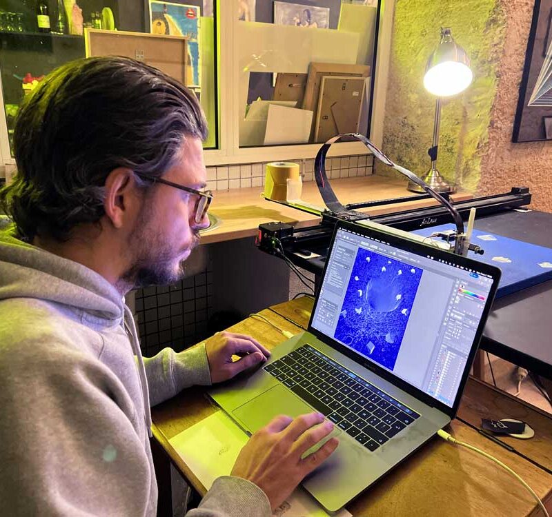 Matthieu Poli face à son ordinateur avec en fond sa Drawing Machine