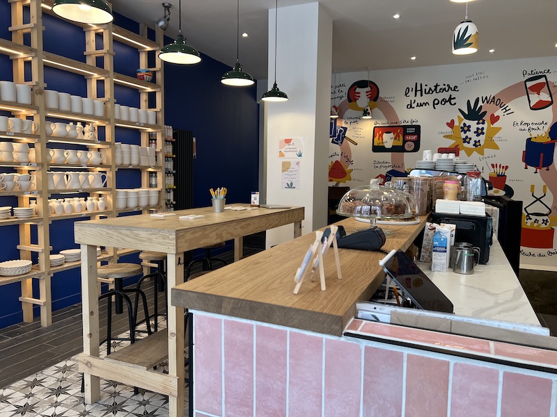 Intérieur de la Papoterie : couleur pop aux murs et bois blond pour les tables