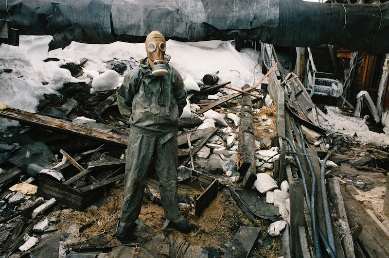 Photo de Françoise Huguier représentant un ouvrier, avec masque et combinaison dans les décombres d'une usine.