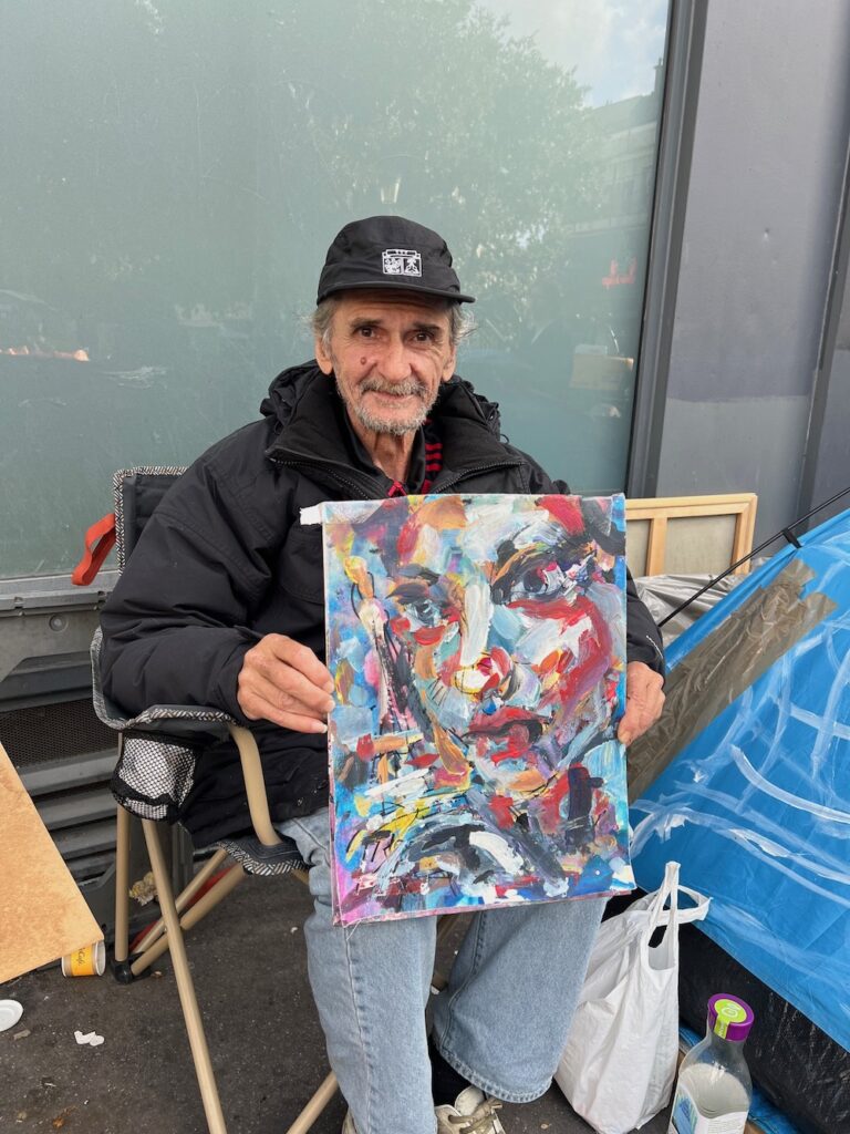 Zfgufa montre un tableau qu'il vend Place Pigalle