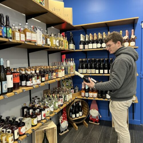 Xavier dans sa boutique avec une bouteille de vin blanc sans alcool