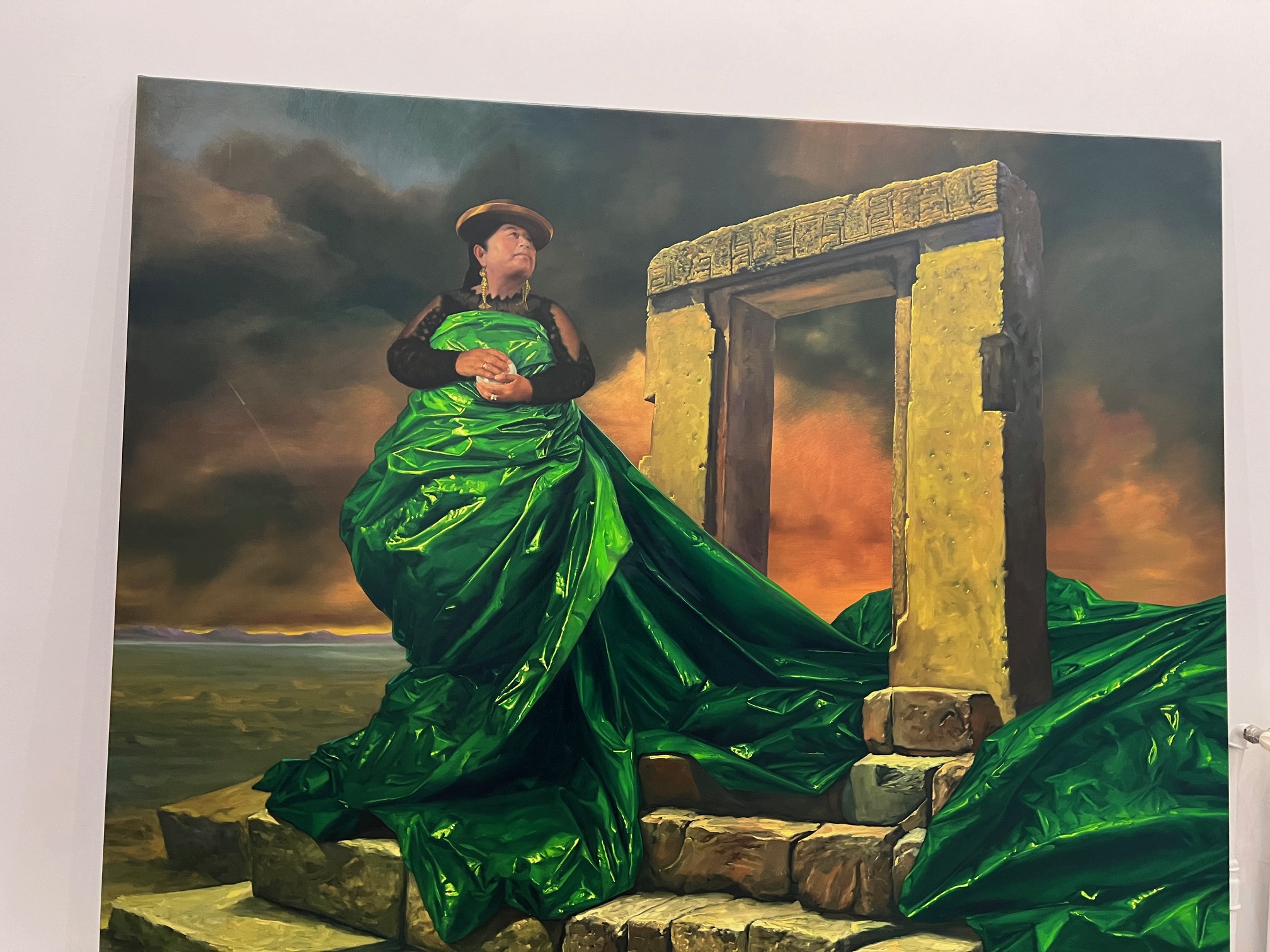 Hija de la Luna (2023), une oeuvre du peintre Cristian Laime représentant une femme bolivienne dans une robe de plastique verte dont les pans tombent sur une ruine de pierre.