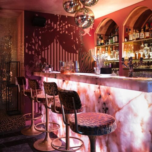 La partie bar du Yago Pigalle avec un comptoir rétro-éclairé, de hautes chaises de bar de velours panthère, des boules à facettes.