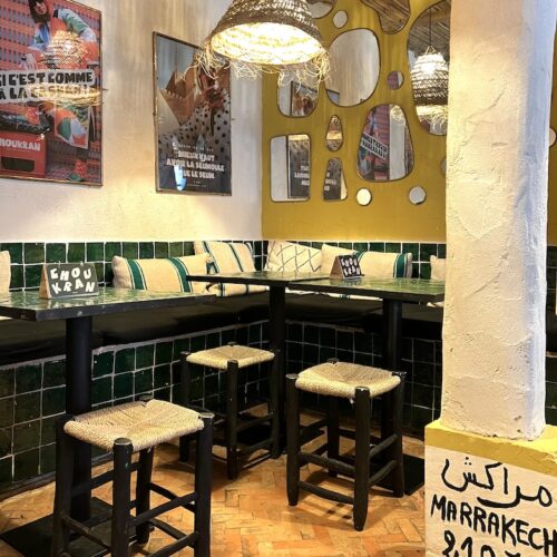 Intérieur du restaurant Choukran avec affiches du Maroc , bancs et tables en zelliges verts et petits tabourets
