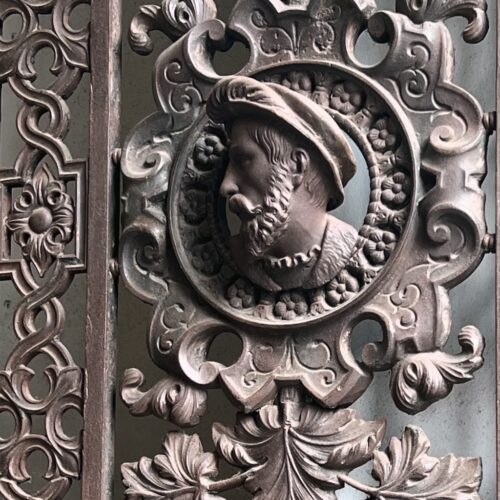 Le visage sculpté d'Abélard de 3/4 sur une porte ouvragée