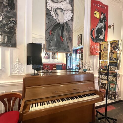 intérieur du café avec un vieux piano droit et des peintures de Montmartre.