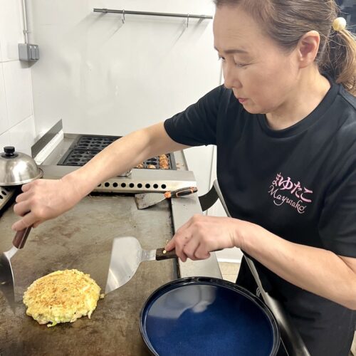 Mayumi e train de retourner une galette sur une plaque chauffante