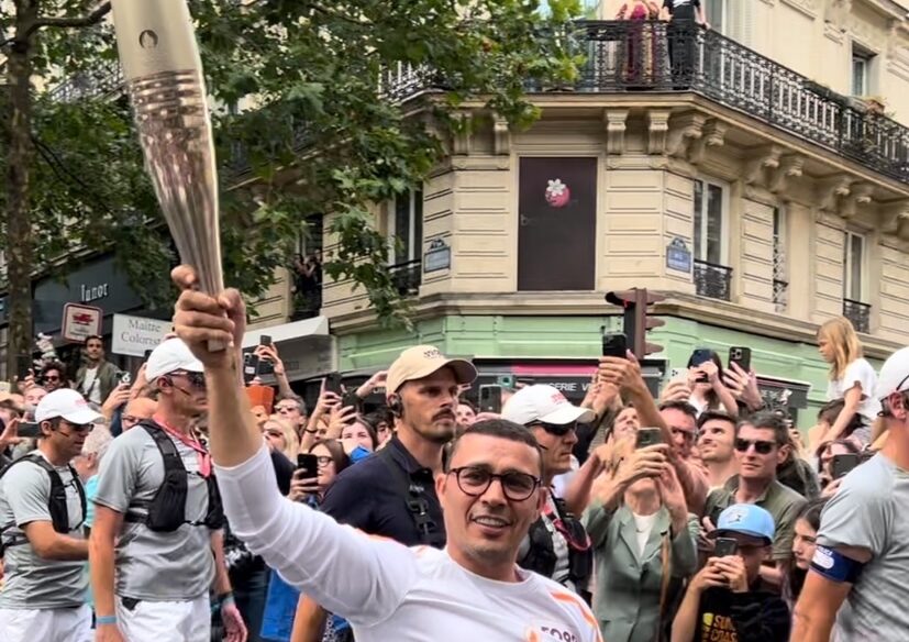 Brahim Asloum portant la flamme olympique rue des Martyrs