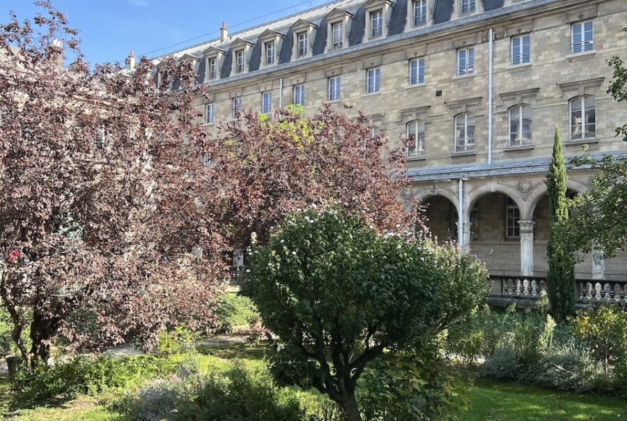 Cour d'honneur du lycée Jacques-Decour avec des arcades et un terre-plein planté.