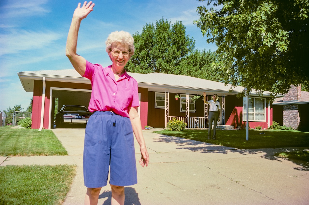 Photo ©Deanna.Dikeman représentant une femme d'une soixantaine d'années en short bleu et chemise rose agitant la main pour dire au revoir