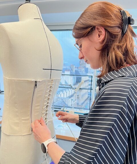 Jeune couturière lace une bustier dans le dos