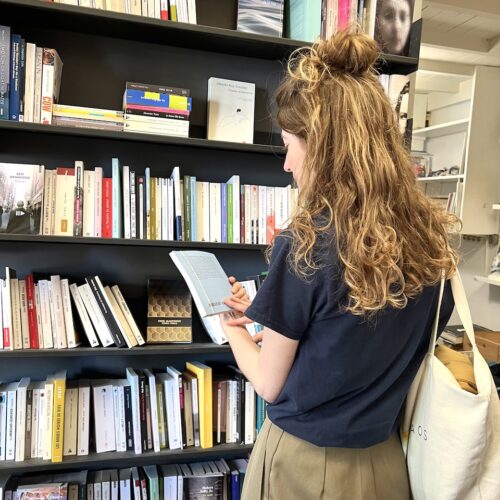 Une cliente au sein de la librairie lit la quatrième de couverture d'un livre
