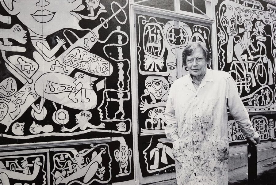 Yvon Taillandier pose devant la fresque murale peinte sur la façade de son atelier