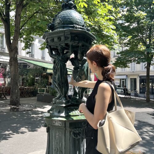 Jeune femme remplissant sa gourde à une fontaine Wallace, place Gustave Toudouze, paris 9e