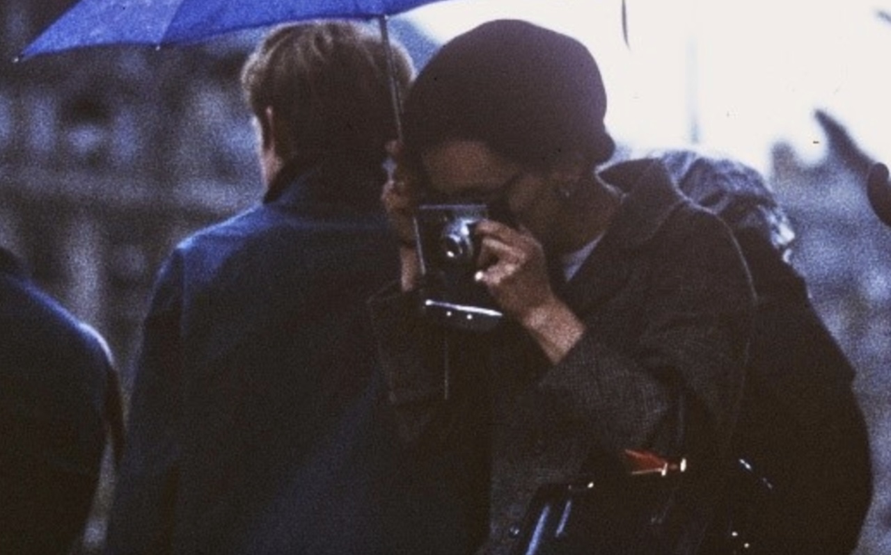 Une femme sous un parapluie en train de prendre une photo