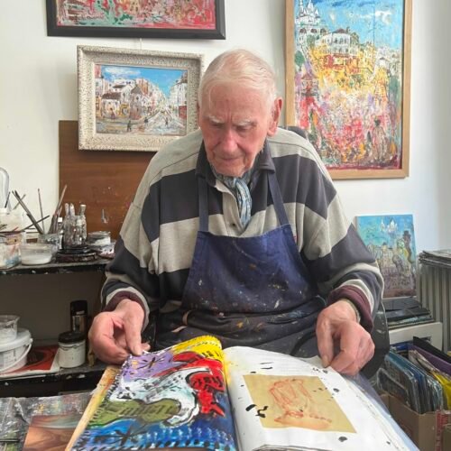 le peintre Bruno Emile Laurent feuillette un catalogue sur lequel il peint
